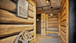 Interior de madera con una gran rueda de madera, un cuadro enmarcado y un letrero con el número 27 en la pared.