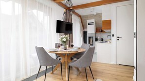 Un comedor moderno con una mesa redonda de madera, cuatro sillas y un televisor montado en la pared.