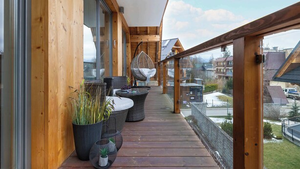 Una terraza de madera con mobiliario de mimbre y plantas en macetas.