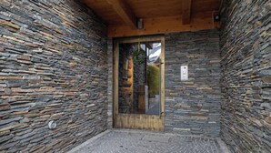 Una entrada de pared de piedra con una puerta de madera y un pequeño espacio exterior con suelo adoquinado.