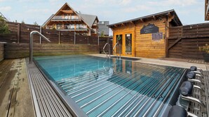 Una cabaña de madera con zona de piscina, que incluye un jacuzzi y una terraza de madera.