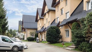 A residential building with a paved driveway, parked cars, and well-maintained greenery. - Family Apartment with Terrace | 2 km to Krupowki and Parking (Zakopane)