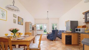 A spacious living area with a dining table, chairs, a sofa, and a kitchen area with cabinets and appliances. - Family Apartment with Terrace | 2 km to Krupowki and Parking (Zakopane)