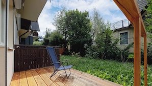 A wooden deck with a blue chair, surrounded by greenery and a fence. - Family Apartment with Terrace | 2 km to Krupowki and Parking (Zakopane)