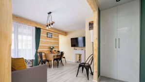 Una sala de estar moderna con sofá, mesa de comedor, sillas, chimenea y televisor montado en la pared.