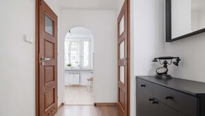 A hallway with wooden doors, a black cabinet, and a window with a view of a building.