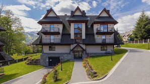 A large, two-story house with a symmetrical facade, multiple balconies, and a driveway leading to the entrance.