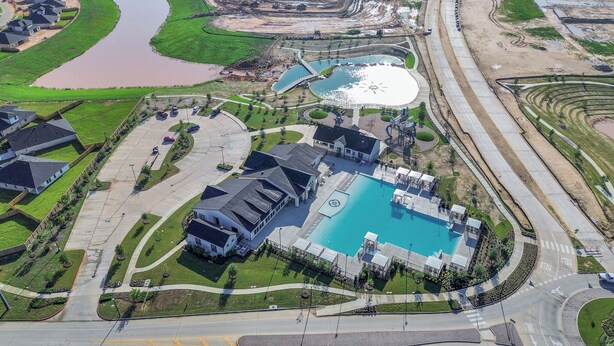 An aerial view of a residential area with a large swimming pool, multiple houses, and a road network. - Marice Serene Home at Katy Fulshear  (Fulshear)
