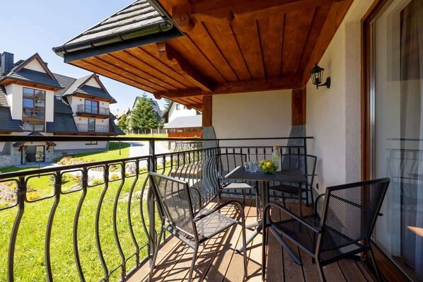 A balcony with a wooden ceiling, metal railing, and a table with chairs.
