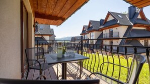 Un balcon avec une table et des chaises, donnant sur une rangée de maisons aux toits inclinés.