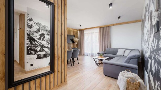 Un salon moderne avec un canapé gris, une petite table basse et un coin repas avec des chaises.