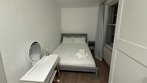 A small, neatly arranged bedroom with a bed, a bedside table with a mirror, and a lamp. - Covent Garden 1-bed Apt Sleeps 4, 7 min to Station (London)