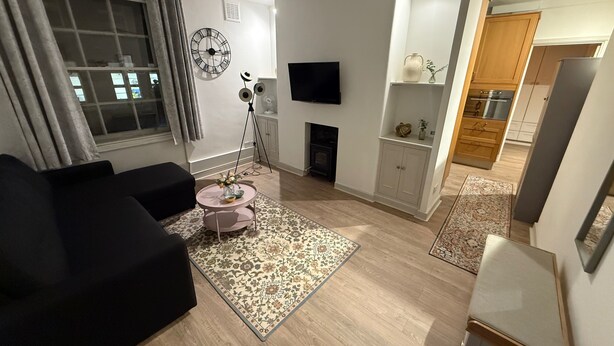 A modern living room with a sofa, a coffee table, a fireplace, a TV, and a kitchen in the background. - Covent Garden 1-bed Apt Sleeps 4, 7 min to Station (London)
