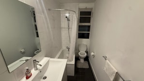 A compact bathroom with a white sink, mirror, and shower. - Covent Garden 1-bed Apt Sleeps 4, 7 min to Station (London)
