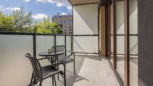 A balcony with a round table and chairs, a glass door, and a view of buildings and trees. - Stylish Apartment in Mokotow | Air Conditioning and Parking (Warszawa)
