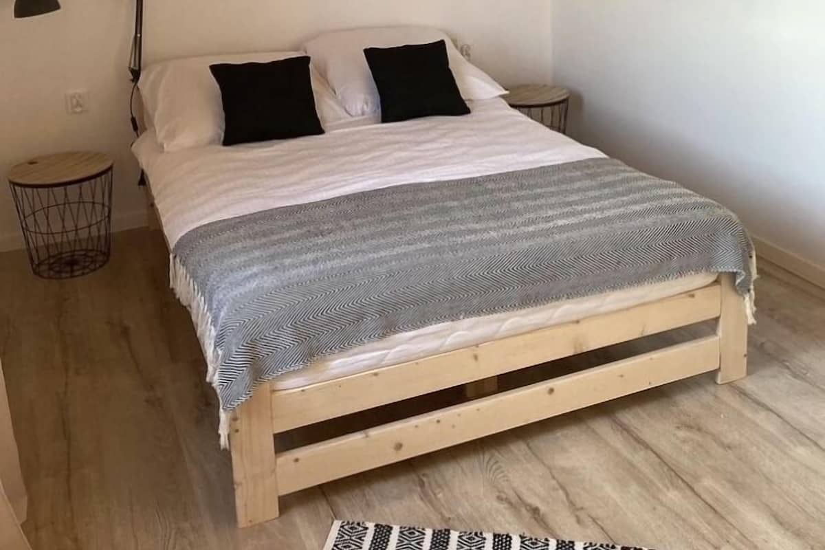 A bedroom with a wooden bed, a bedside lamp, and two framed pictures on the wall.