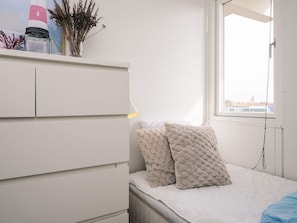 A bedroom with a bed, a window, and a white wardrobe.