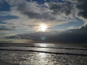 A beach with waves and a cloudy sky.