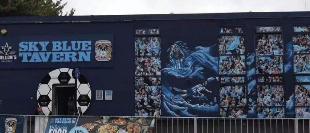 A building with a mural of a blue figure and the text 'Sky Blue Tavern.'