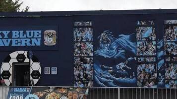 A building with a mural of a blue figure and the text 'Sky Blue Tavern.'