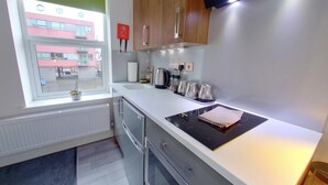 Uma cozinha moderna com forno embutido, fogão e janela com vista para um prédio.
