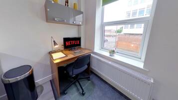 A small office space with a desk, chair, computer, and a window.
