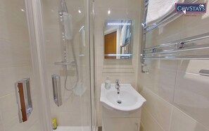 A modern bathroom with a glass-enclosed shower, a white sink, and a mirror above it. - Victoria House by CovStays (Coventry)