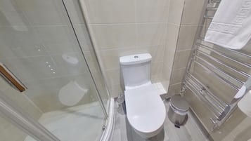 A modern bathroom with a toilet, a glass shower enclosure, and a towel rack.
