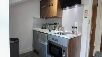 A compact kitchen with a built-in oven, a microwave, and a sink.