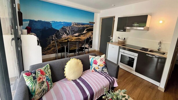 A compact living space with a sofa, a small kitchen area, and a dining table.