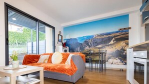 A modern living room with a sofa, dining table, and kitchen area.