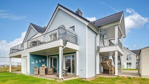 Een huis met twee verdiepingen, een overdekte veranda, een garage en een klein terras.