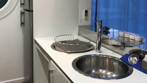 A modern kitchen with a stainless steel sink, a wire fruit basket, and a can of Corona beer on the shelf. - Rented T2 independent shared pool at home Near beaches. (Perpignan)