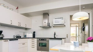 A modern kitchen with white cabinets, a stainless steel oven, a microwave, and a coffee machine. - 4 Person Holiday Home in Ringkobing (Ringkobing)