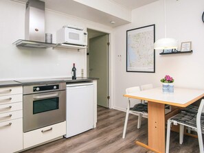 A modern kitchen with a microwave, oven, and dishwasher. There is a dining table with chairs and a map on the wall. - 4 Person Holiday Home in Ringkobing (Ringkobing)