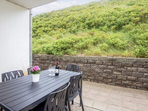 A patio table with chairs, a bottle of wine, and a potted plant. - 4 Person Holiday Home in Ringkobing (Ringkobing)