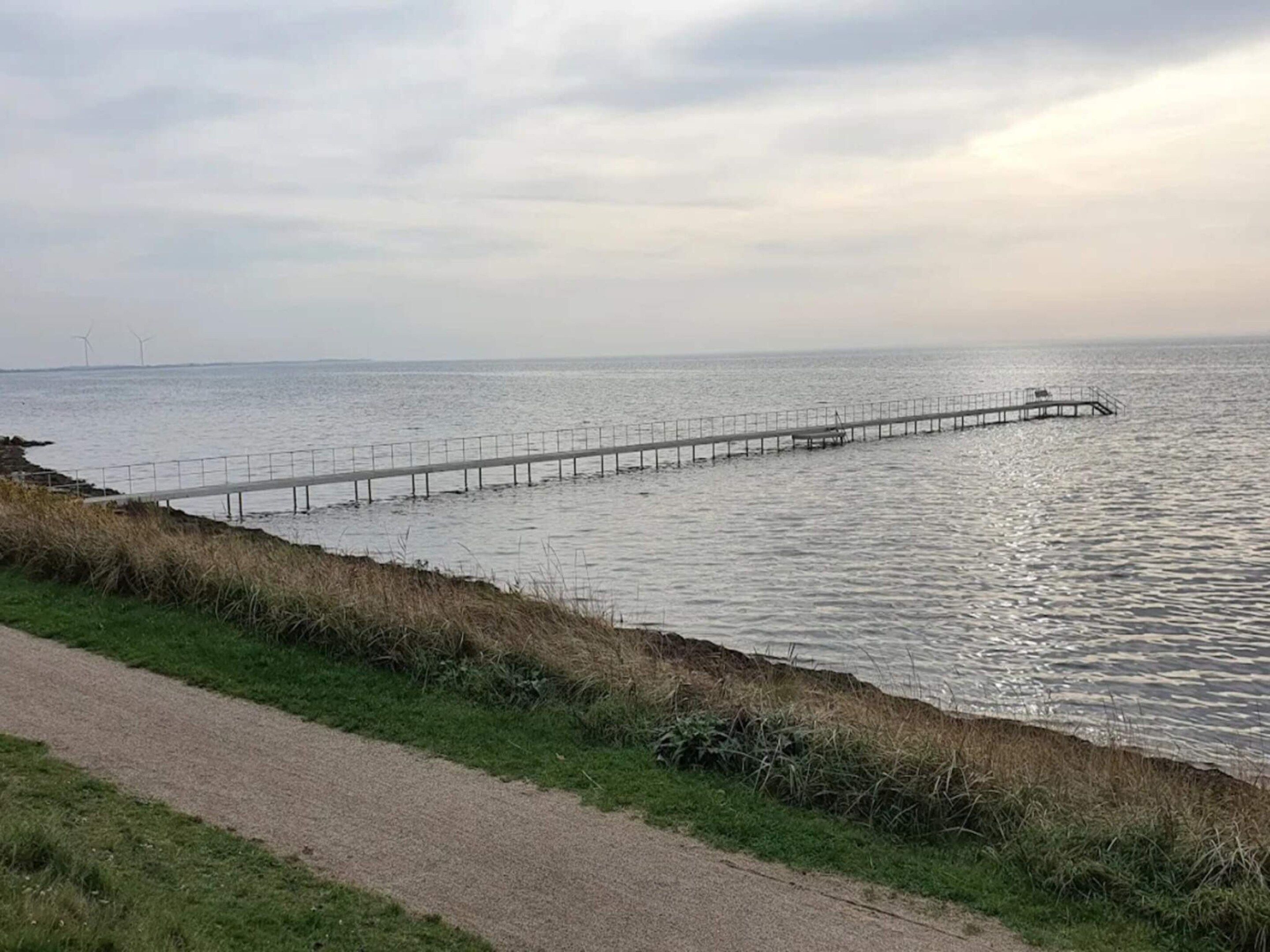 A coastal walkway leading to a pier extending into the sea.