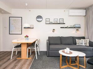 A modern living room with a dining table, sofa, and a small round table with candles. - 4 Person Holiday Home in Ringkobing (Ringkobing)
