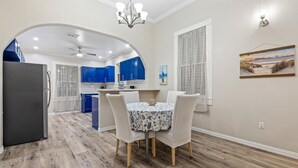 Una cocina moderna con armarios azules, un comedor con mesa redonda y vista al área de estar a través de un arco.