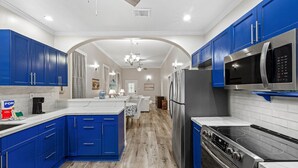 Una cocina moderna con armarios azules, electrodomésticos de acero inoxidable y suelo de madera.