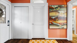 Un corridoio con una porta bianca, una porta a persiana bianca e un quadro di pesci colorati al muro.