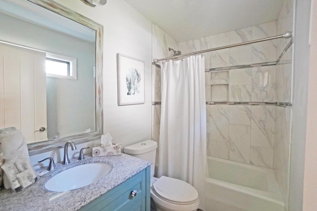 Un bagno con lavandino bianco, specchio, WC e doccia con porta in vetro.