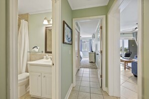 Un pasillo con un baño a la izquierda, un comedor a la derecha y un dormitorio al fondo.