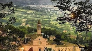 Une ville historique abritant une église remarquable, reconnaissable à son imposant clocher, et entourée d’une végétation luxuriante et de bâtiments traditionnels.