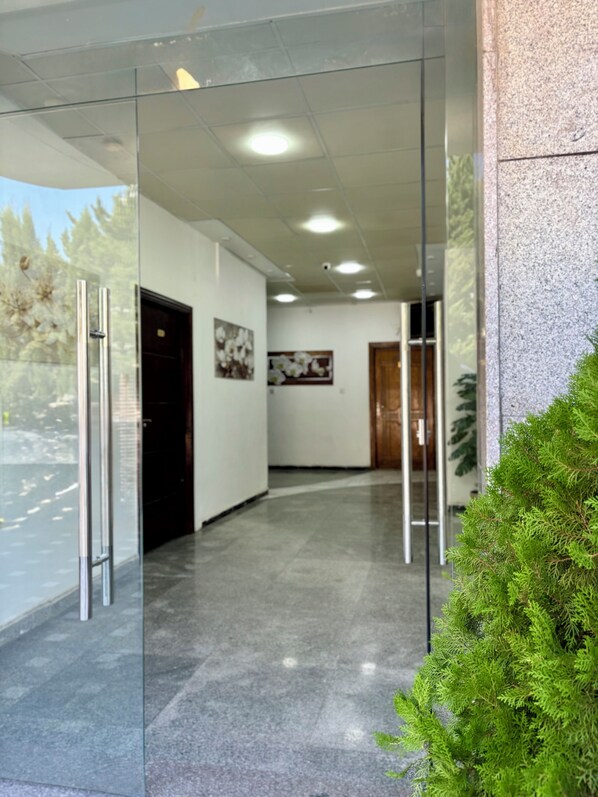 A hallway with glass doors, a framed picture on the wall, and a potted plant.