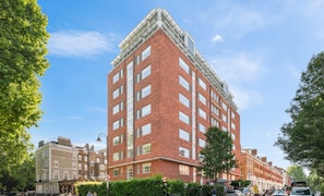 A multi-story red brick building with a corner entrance, large windows, and a flat roof.