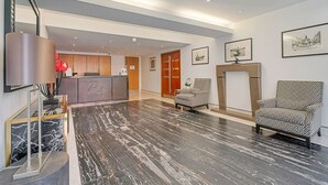Een ruime lobby met een marmeren vloer, een receptiebalie en gestreept fauteuilstoelen.