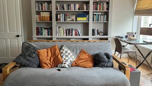 A living room with a grey sofa, multiple bookshelves, a wooden coffee table, and a small desk with a chair. - Contemprary central London 5 bed townhouse (London)