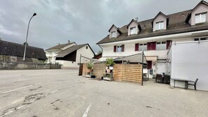 A parking lot with a row of houses, a street lamp, and a covered area with tables and chairs. - ZIMMERzuVERMIETEN.ch Flumenthal SO (Flumenthal)