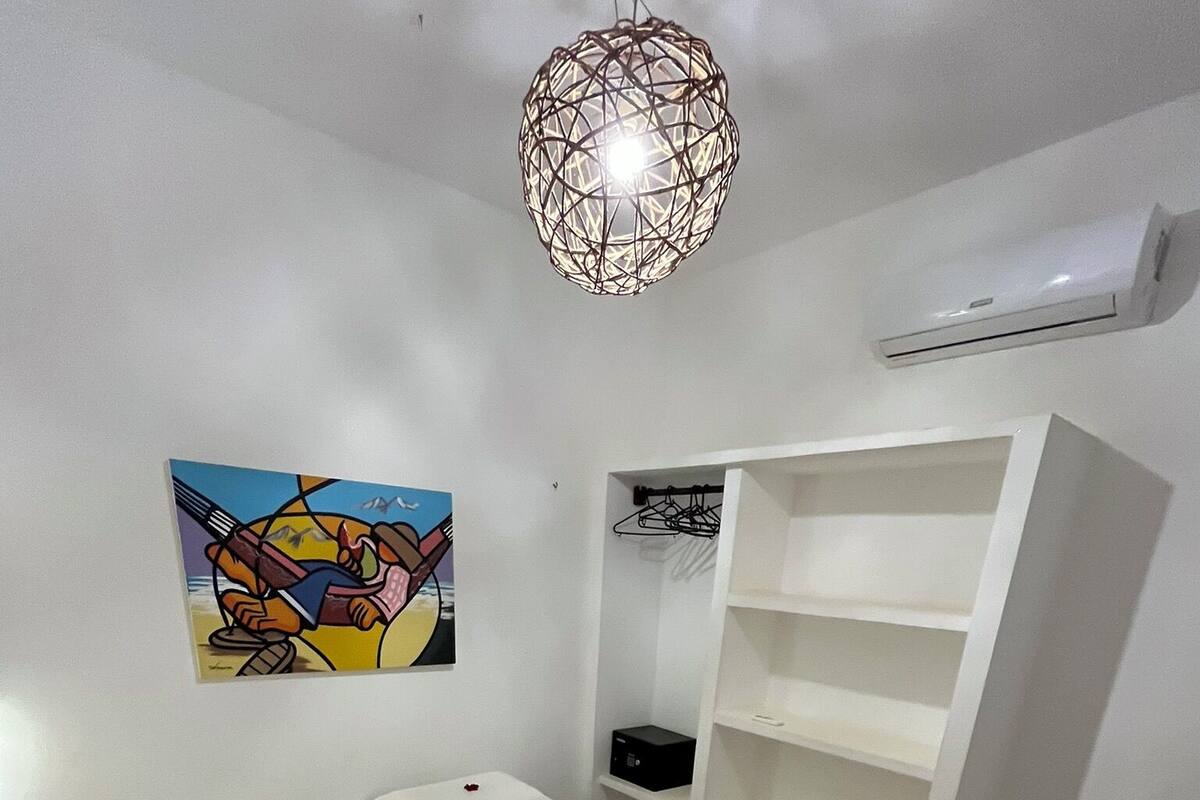 Habitación de hotel con cama, un cuadro, un armario y una lámpara colgante.